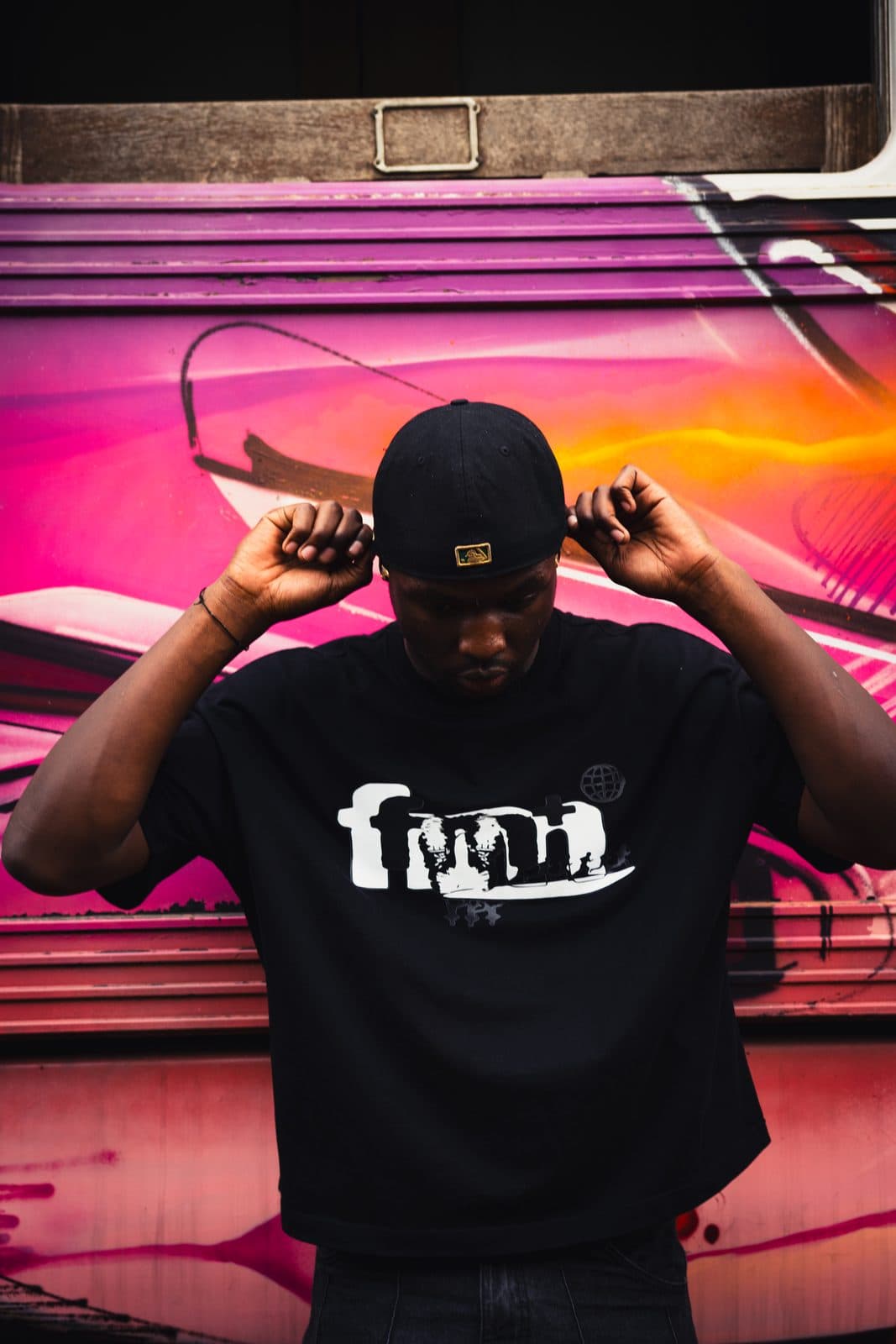 Black tee with a white chest graphic, against a painted carriage