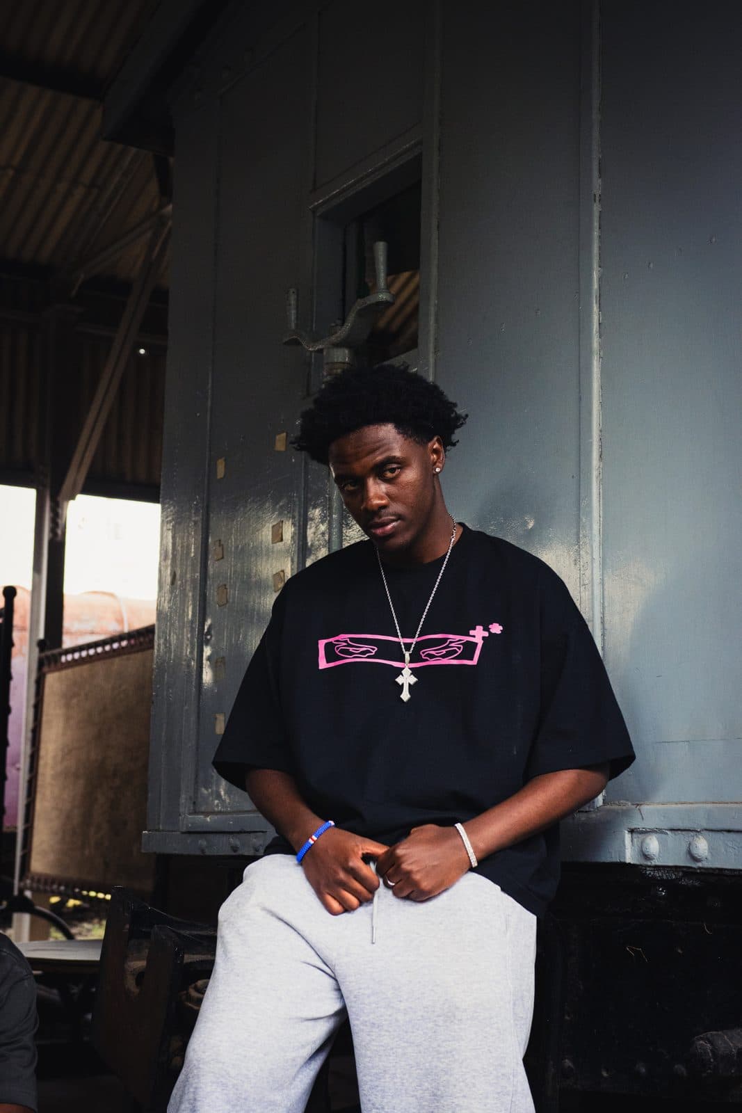 Oversized black tee with a pink graphic, beside a goods wagon