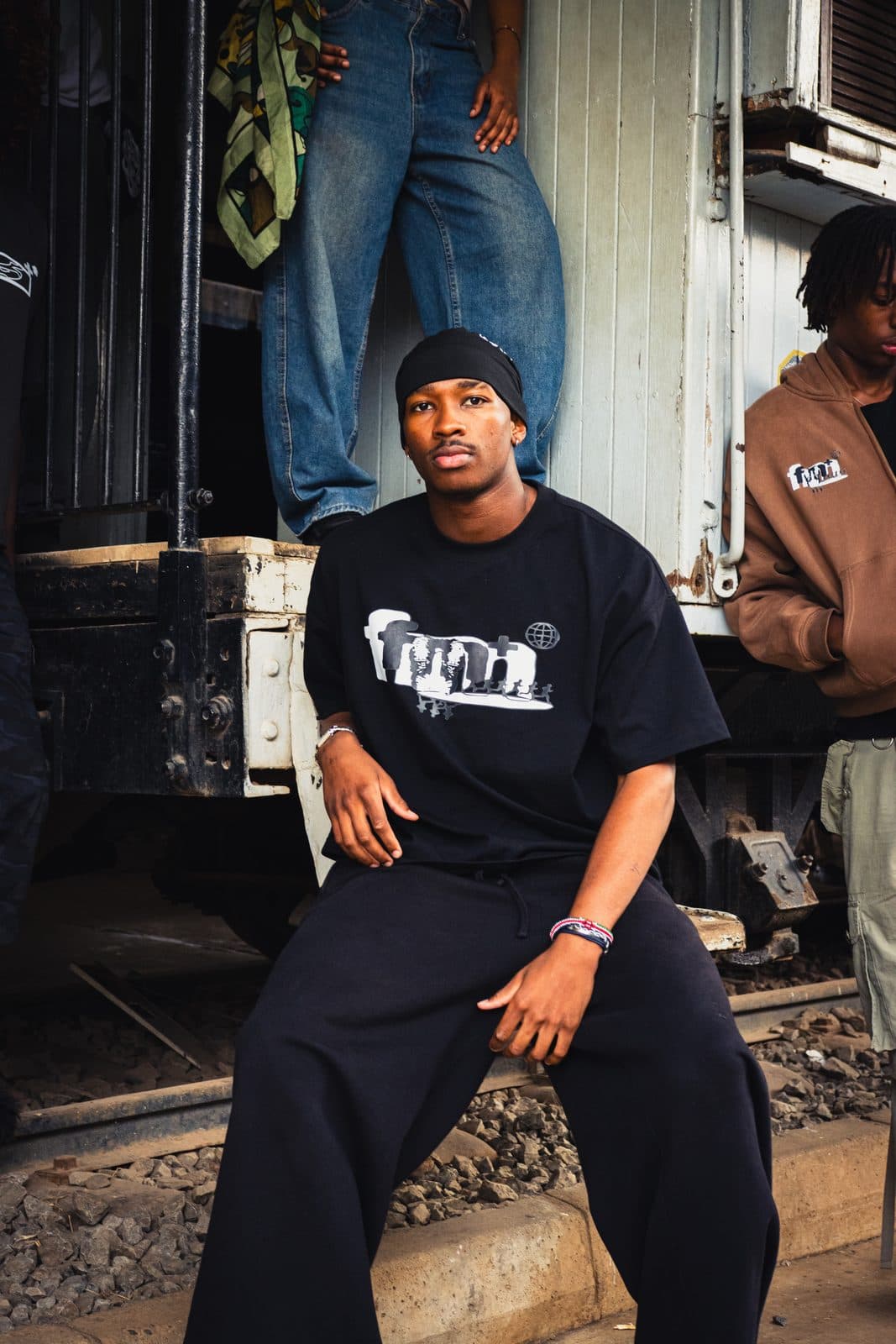 Black tee with a white chest graphic, seated on the rails
