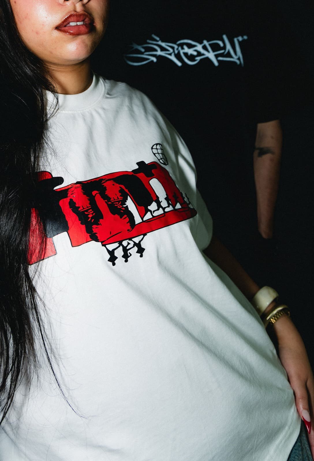 Close crop of the From NBO With Love Tee in Cream / Crimson Rage, worn in the train yard.